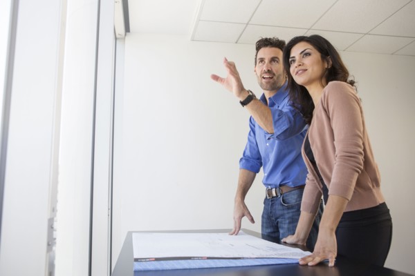 Business people examining blueprints in office