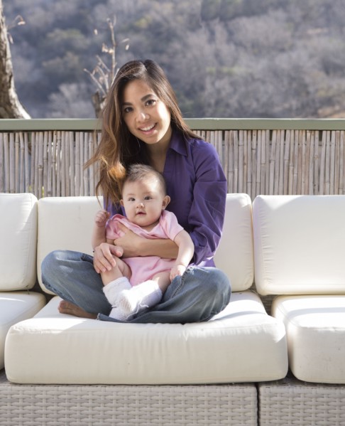 Mother holding baby girl on patio sofa