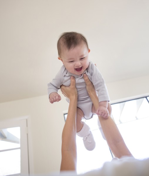 Mother holding baby girl overhead