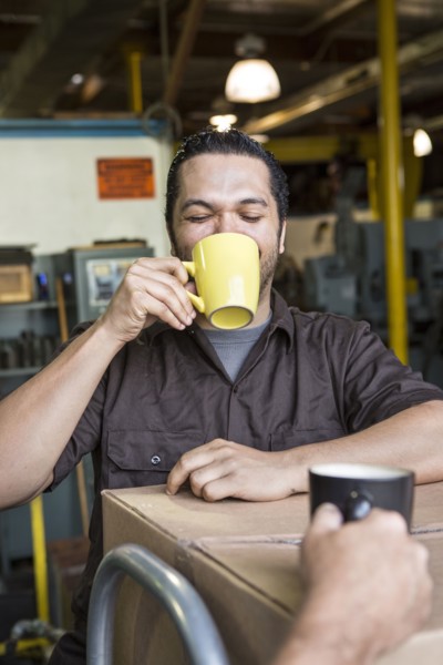 Worker drinking coffee in warehouse