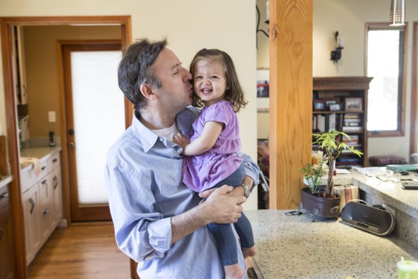 Father kissing daughter in kitchen
