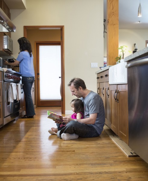 Father reading to daughter in kitchen
