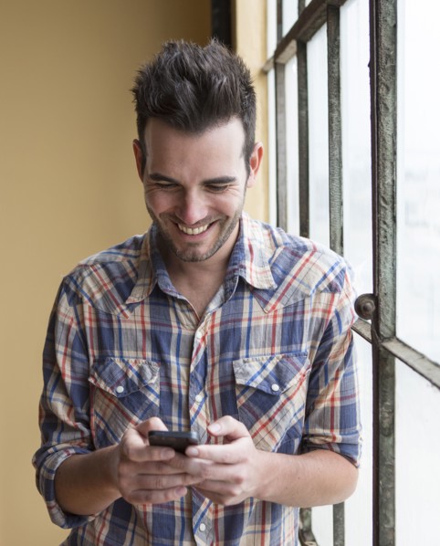 Caucasian man using cell phone by window