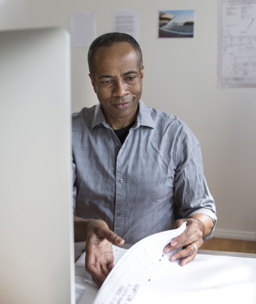 African American architect examining blueprints in office
