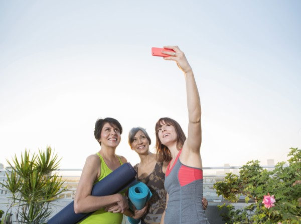 Women taking cell phone selfie on urban rooftop