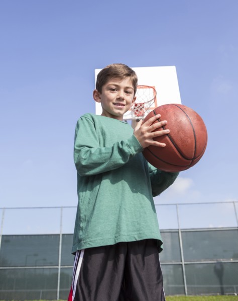 Low angle view of Caucasian boy holding basketball on court