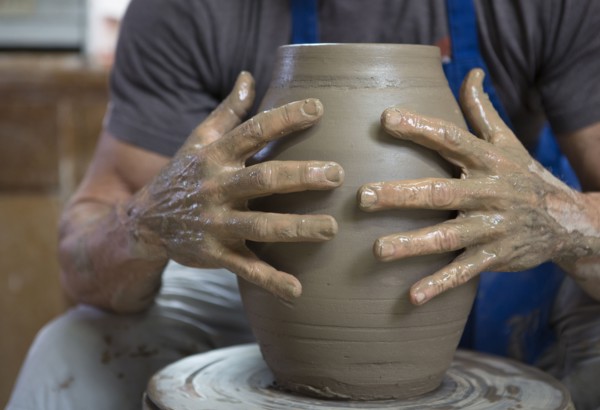 Older Caucasian man forming pottery on wheel in ceramics studio
