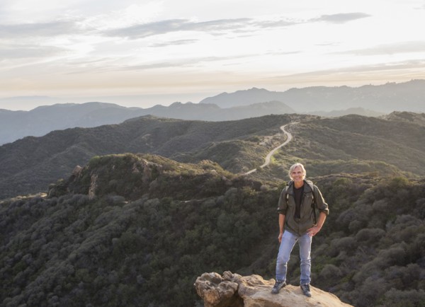 Older Caucasian man standing on rocky hilltop
