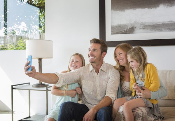 Caucasian family taking selfie on sofa
