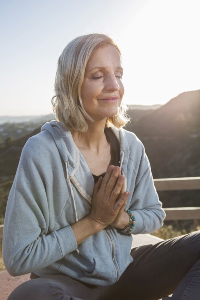 Caucasian woman meditating on hilltop