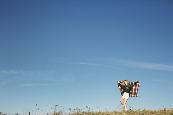 Caucasian woman playing with scarf on hilltop