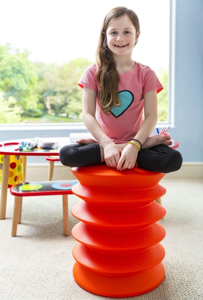 Caucasian girl sitting cross-legged on stool in playroom