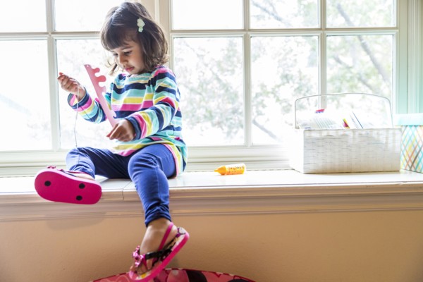 Girl playing with toys in windowsill