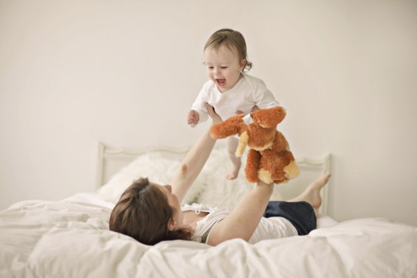 Caucasian mother playing with baby on bed