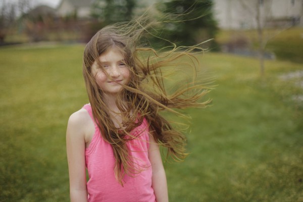 Hair of Caucasian girl blowing in wind in backyard