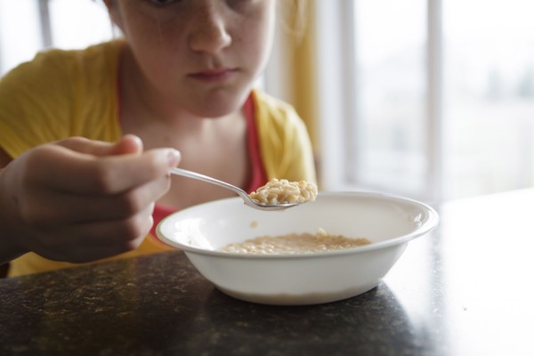 Caucasian girl eating breakfast at table