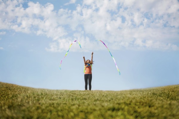 Caucasian girl playing with ribbons on hilltop