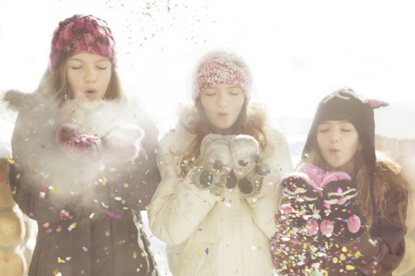 Caucasian girls blowing snow off mittens