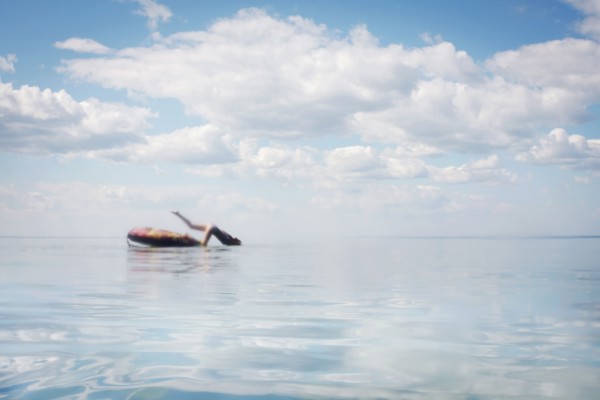 Caucasian teenage girl jumping from inner tube into lake