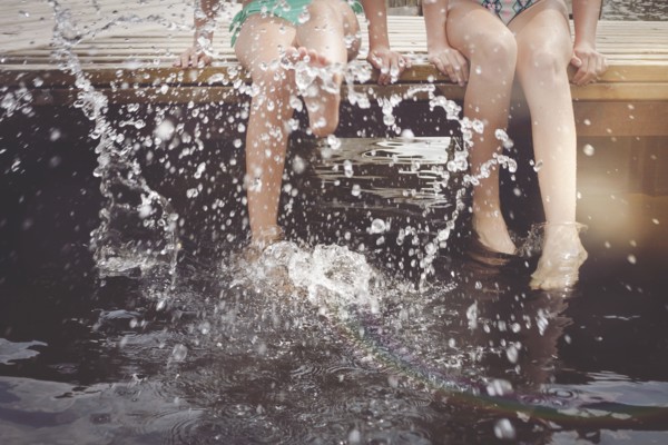 Caucasian girls splashing in lake from wooden dock