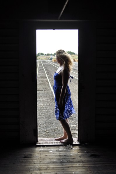 Woman standing in doorway of train in train yard