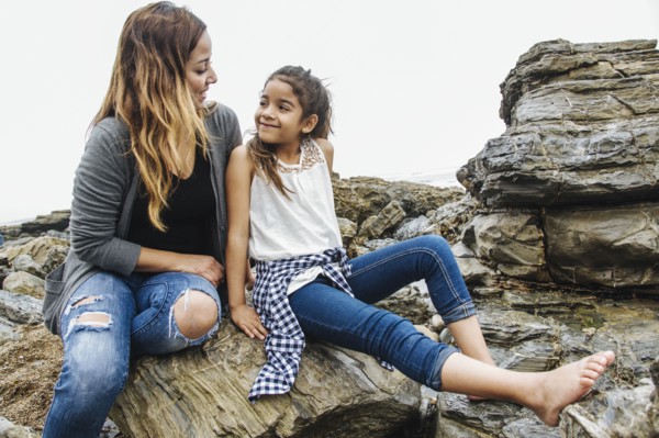 Hispanic mother and daughter sitting at tide pools