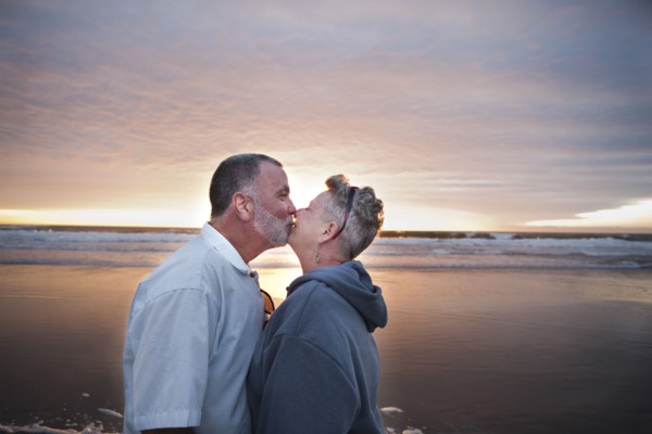 Caucasian couple kissing on beach at sunset