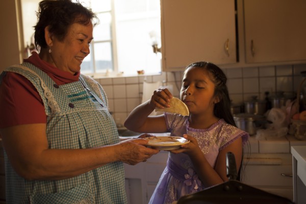 Hispanic woman cooking for granddaughter in kitchen