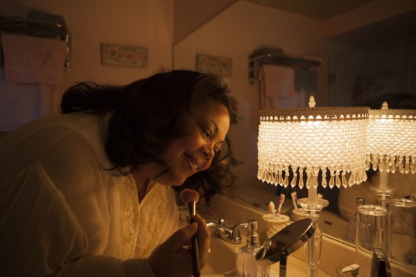 Woman applying makeup in bathroom mirror