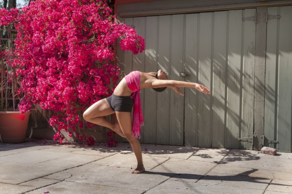Woman practicing yoga near flowers and fence
