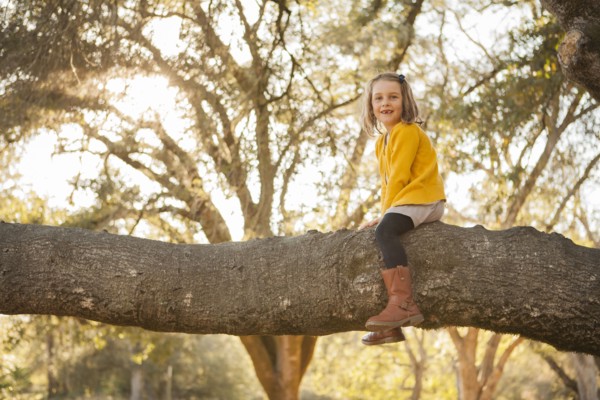 Girl sitting on tree branch in park
