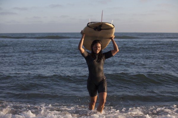 Hispanic surfer carrying surfboard in ocean