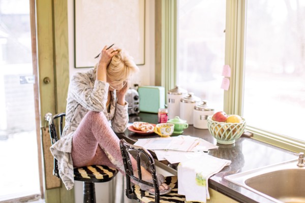 Caucasian woman paying bills on telephone in kitchen