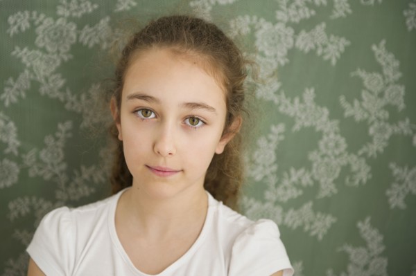 Close up of somber Caucasian girl near wallpaper