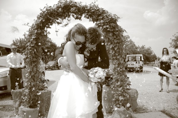 Caucasian bride and groom walking through archway