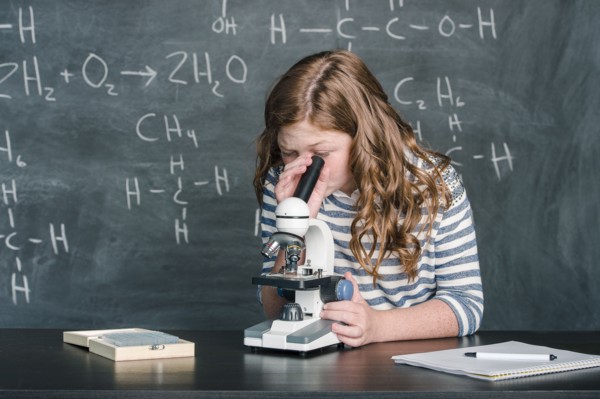 Caucasian student using microscope in science class