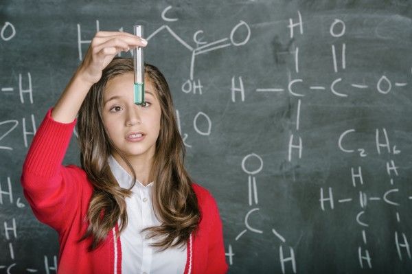 Hispanic student examining test tube in science class