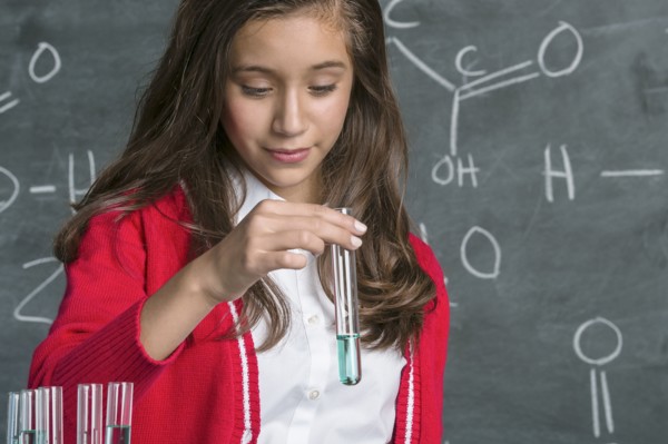 Hispanic student examining test tube in science class