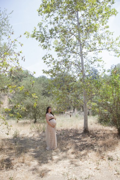 Pregnant Caucasian woman standing in forest