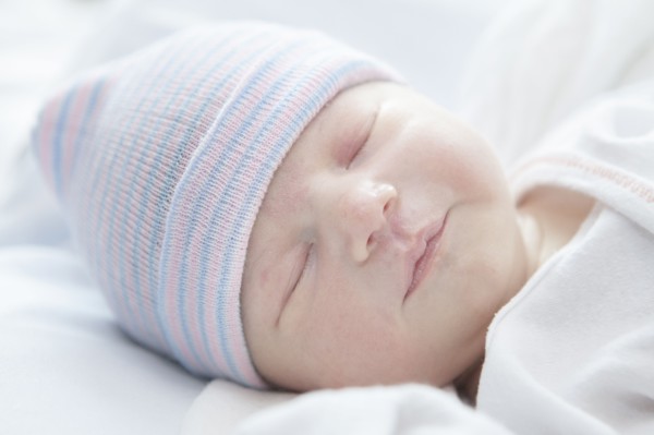 Caucasian newborn girl wearing cap