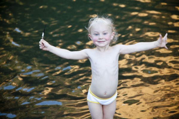 Smiling girl standing with arms outstretched at lake