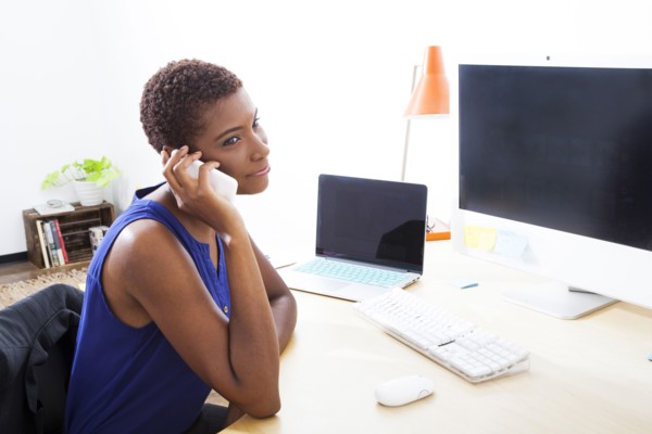 Black businesswoman talking on cell phone at office desk