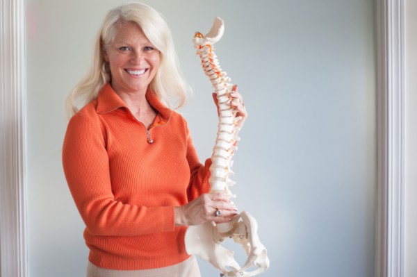 Caucasian chiropractor holding model spine