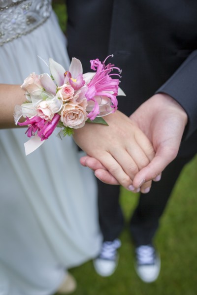 Close up of teenage couple holding hands in prom attire