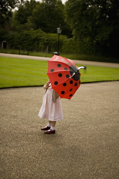 Girl standing under umbrella in park