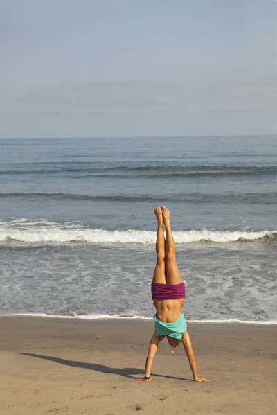 Caucasian woman doing handstand on beach