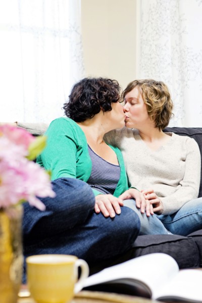Lesbian couple kissing on sofa in living room