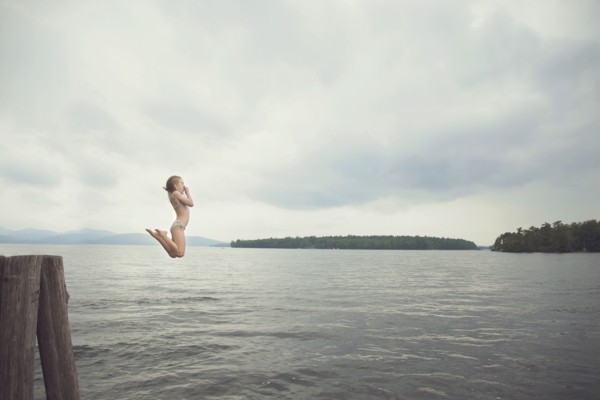 Caucasian girl jumping in remote lake