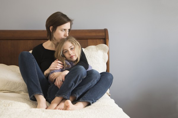 Caucasian mother cuddling daughter on sofa