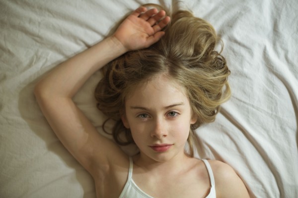 Serious Caucasian girl laying on bed
